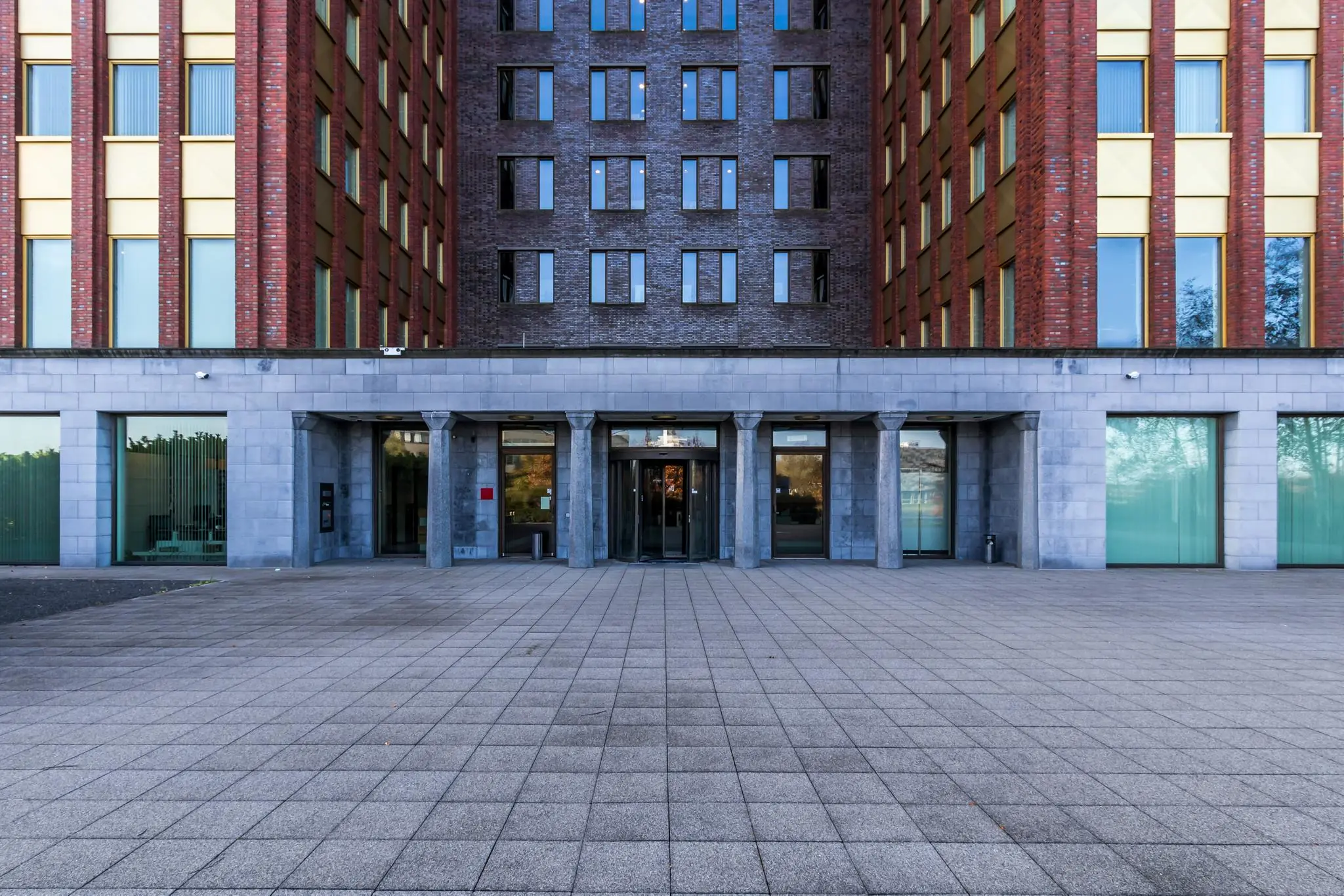 Ingang van een modern kantoorgebouw aan de Fascinatio Boulevard met grijze natuurstenen gevel en glazen draaideur.